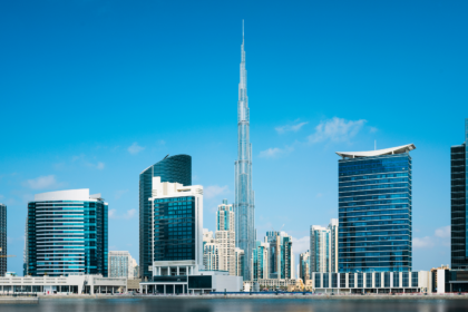 A clear daytime view of Dubai’s iconic skyline with the towering Burj Khalifa surrounded by modern skyscrapers reflected on calm waters — a stunning showcase of the top attractions in Dubai, including architectural marvels, luxury hotels, shopping hubs, and breathtaking urban views.