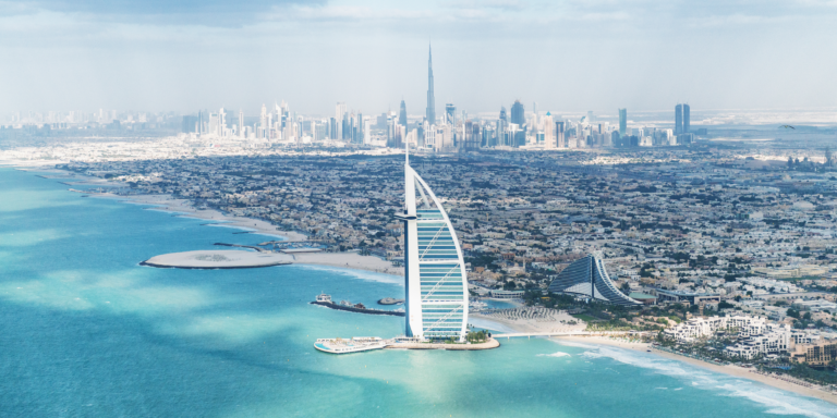 Aerial view of Dubai with the Burj Al Arab and city skyline, showing how you can experience luxury and sights even when exploring Dubai on a budget.