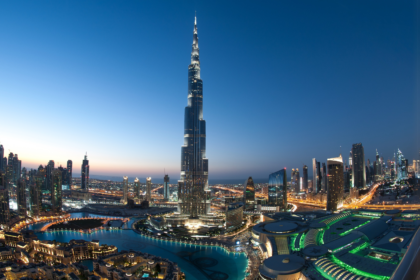 Evening skyline of Dubai featuring the iconic Burj Khalifa, with city lights reflecting modern architecture, used as a banner for a blog on Tourist Attractions in Dubai with a complete guide