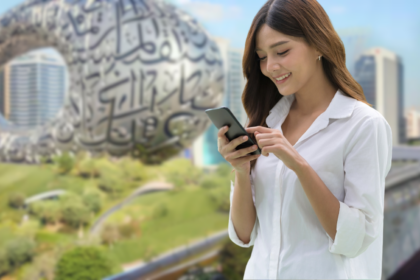 Young woman using mobile phone in Dubai with Museum of the Future in background, showing the importance of choosing the right SIM card for Dubai to stay connected.