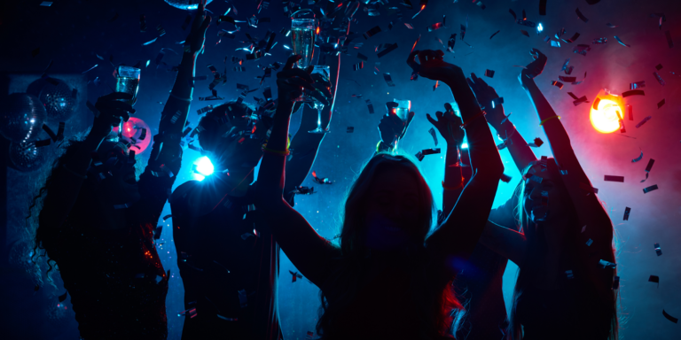 Group of friends partying with drinks and confetti at a vibrant nightclub, representing where to party in Dubai for unforgettable nightlife experiences.