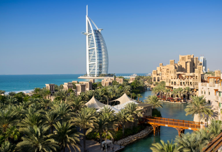 Iconic view of Burj Al Arab and traditional souk area in Dubai with lush palm trees, perfect for Dubai from India travel guides.