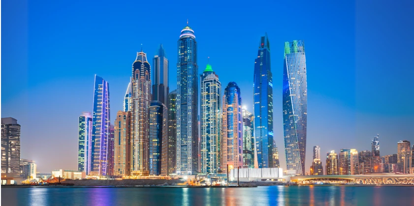 Colorfully illuminated skyscrapers of the Dubai Marina skyline at dusk, viewed across the waterfront, representing the vibrant atmosphere and modern cityscape where top Dubai festivals take place throughout the year.