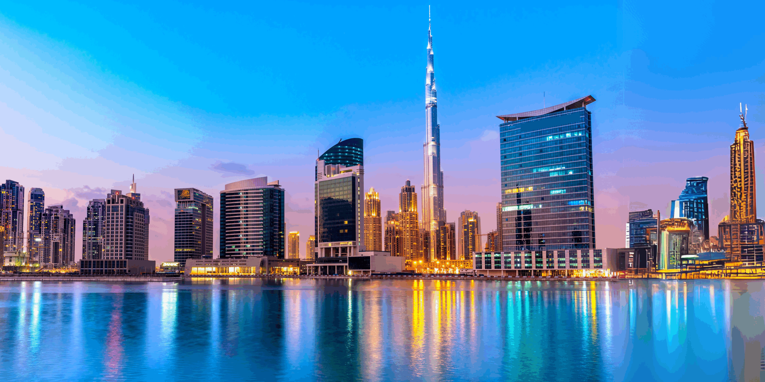 A dazzling view of Dubai’s skyline at dusk, featuring the iconic Burj Khalifa and modern high-rise buildings reflected in calm waterfront waters, capturing the glamour and vibrancy perfect for a stylish girls trip to Dubai.