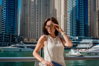 Woman wearing sleeveless lace dress and sunglasses at Dubai Marina illustrating what not to wear in Dubai due to cultural dress code norms