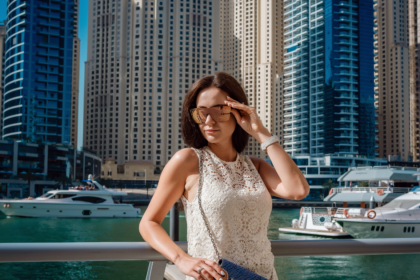 Woman wearing sleeveless lace dress and sunglasses at Dubai Marina illustrating what not to wear in Dubai due to cultural dress code norms