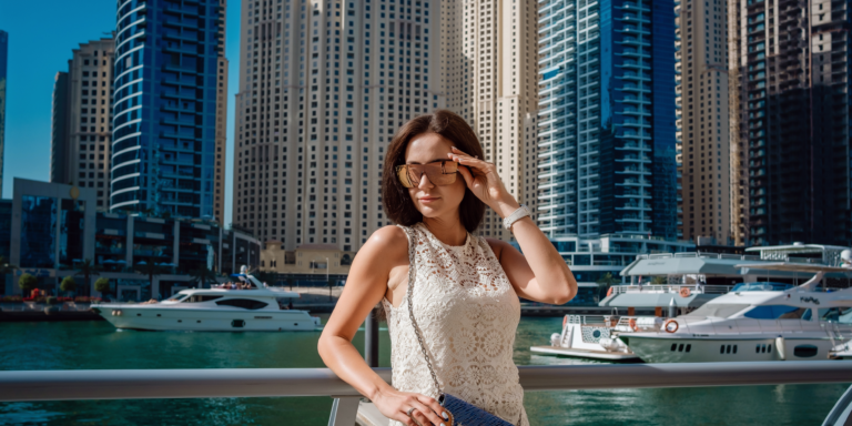 Woman wearing sleeveless lace dress and sunglasses at Dubai Marina illustrating what not to wear in Dubai due to cultural dress code norms