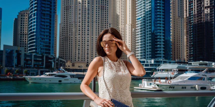 Woman wearing sleeveless lace dress and sunglasses at Dubai Marina illustrating what not to wear in Dubai due to cultural dress code norms